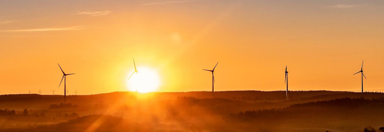 wind turbines facing a sunset